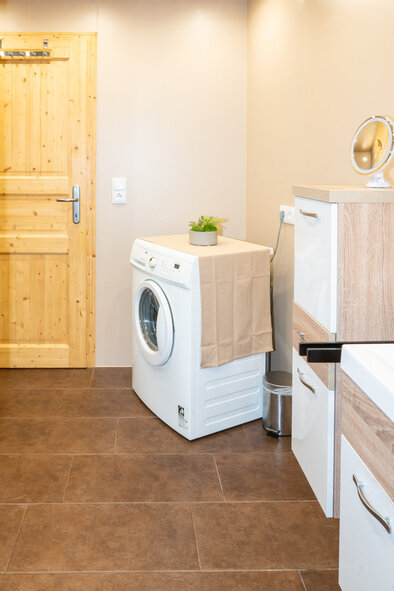 Badezimmer mit Waschmaschine und Zirbenholztür